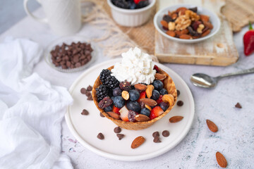 Yogurt and fruit in a waffle bowl. Greek yogurt in ice cream waffle bowl with fruit and nuts, healthy diet friendly dessert. Fruity waffle bowl.