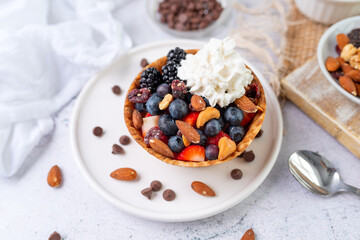 Yogurt and fruit in a waffle bowl. Greek yogurt in ice cream waffle bowl with fruit and nuts, healthy diet friendly dessert. Fruity waffle bowl.