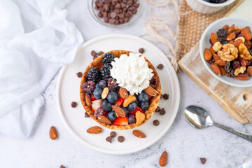 Yogurt and fruit in a waffle bowl. Greek yogurt in ice cream waffle bowl with fruit and nuts, healthy diet friendly dessert. Fruity waffle bowl.
