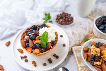 Yogurt and fruit in a waffle bowl. Greek yogurt in ice cream waffle bowl with fruit and nuts, healthy diet friendly dessert. Fruity waffle bowl.