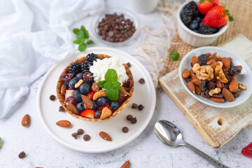 Yogurt and fruit in a waffle bowl. Greek yogurt in ice cream waffle bowl with fruit and nuts, healthy diet friendly dessert. Fruity waffle bowl.