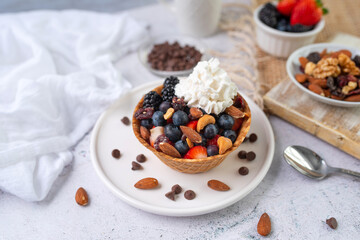 Yogurt and fruit in a waffle bowl. Greek yogurt in ice cream waffle bowl with fruit and nuts, healthy diet friendly dessert. Fruity waffle bowl.