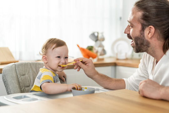 Caucasian Beautiful Father Take Care Of Baby Boy Toddler In Kitchen. 