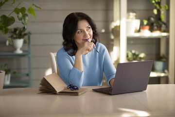 a 35-year-old woman sits at a computer and looks pensively, online work