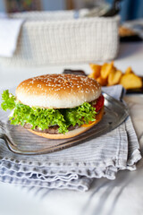 Caprese burger with mozzarella cheese, tomatoes, cucumbers and ham. Given on a glass dish from a transparent bottle. Light background