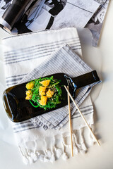 Japanese chuka salad with seaweed and orange. Served on a dark glass dish from a melted black bottle