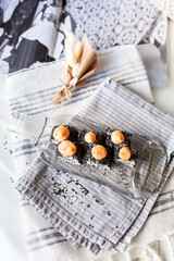 Japanese sushi food. Maki and rolls with tuna, salmon, shrimp, crab and avocado. Served on a glass transparent dish from a melted light bottle
