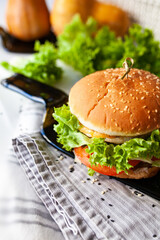 Caprese burger with mozzarella cheese, tomatoes, cucumbers and ham. Given on a glass dish from a transparent bottle. Light background