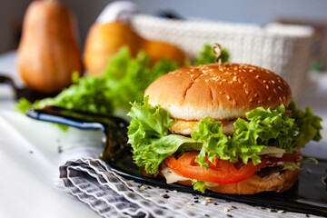 Caprese burger with mozzarella cheese, tomatoes, cucumbers and ham. Given on a glass dish from a transparent bottle. Light background