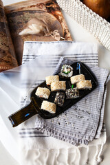 Japanese sushi food. Maki and rolls with tuna, salmon, shrimp, crab and avocado. Served on a dark glass dish from a melted black bottle