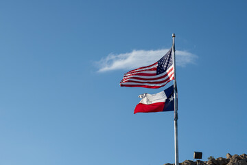 United States and Texas Flag Waving in the Wind Blue Sky