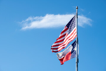 United States Flag and Texas Flag on a Flag Pole Blue Sky