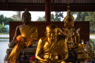 Three beautiful golden Buddha statues sitting and meditating outside in front of a temple in Hua Hin Thailand.