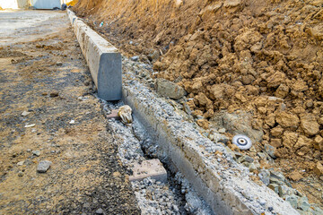 Installation of a curbstone along the edge of a new road, in a residential area under construction