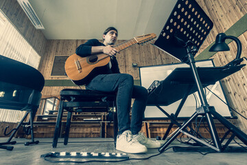 Man playing acoustic guitar and making soundcheck in modern recording studio