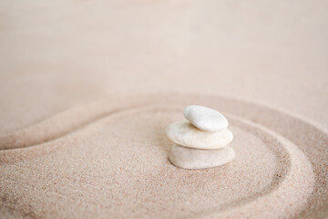 Stacks of pebbles with  pattern Zen japanese garden design on sand beach. Buddhism mind-scape calm stone symbols.