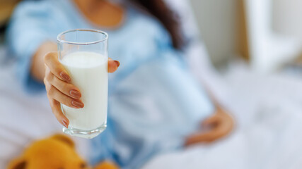 Mom hold drinking glass of healthy milk beverage for calcium nourishment and protein nutrient of pregnant woman as diet for prenatal care for strong birth benefit of unborn baby