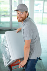 Naklejka na ściany i meble male worker using hand truck carrying a washer