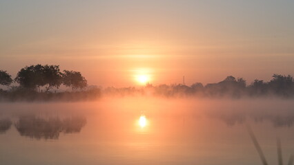 Trees and white clouds on blue sky with reflective in the water.Natural landscape in the morning time.