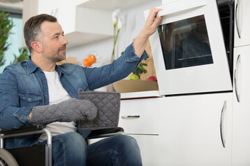 middle aged man is opening his oven in the kitchen
