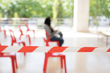 Row of empty red chairs and warning tape infection area.No entry sign concept.Selective focus.