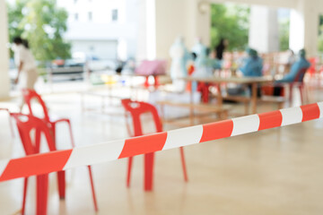 Row of empty red chairs and warning tape infection area.No entry sign concept.Selective focus.