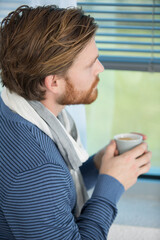 handsome man standing by window and holding coffee cup