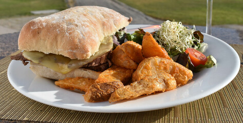 Torta de carne, queso, ensalada y papa en gajo al aire libre, panini especial de carne emplatado gourmet