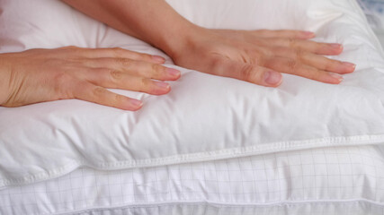 Fototapeta na wymiar Young woman touching soft white pillow, closeup. how to choose a pillow, artificial filling