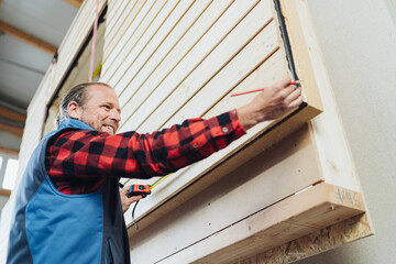 Happy young male worker in a prefabricated woodworking factory