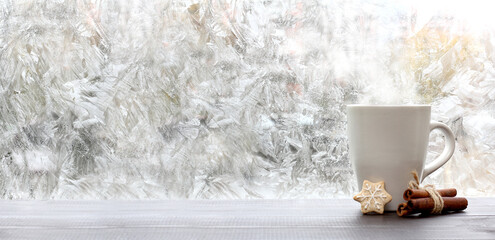 Obraz na płótnie Canvas frosty patterns on the window and a mug of cookies and cinnamon. warming coffee overlooking a winter morning