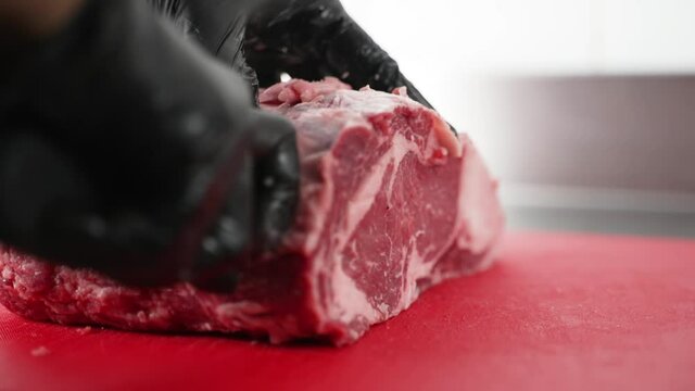 butcher cuts a large piece of selected meat on a steel table