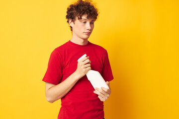 Young curly-haired man in a red t-shirt detergents in hands posing Lifestyle unaltered