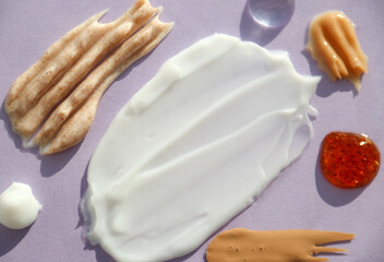 Cosmetic smears of creams, scrub and cosmetic oils on a very peri background close-up. Stylish concept of organic creams and essences, beauty and health products. Body and skin care, hydration