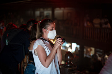 Young girl wearing face mask taking photos at indoor theatrical event