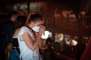 Young girl wearing face mask taking photos at indoor theatrical event