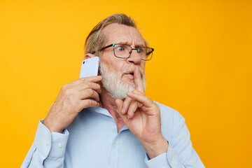 Portrait elderly man in a blue shirt and glasses talking on the phone unaltered