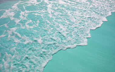 Fototapeta na wymiar Pop art surreal style ocean waves splashing on pale turquoise colored sand beach