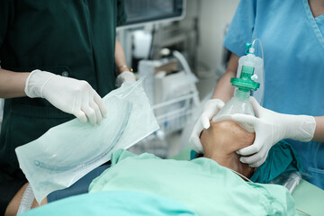 Anesthetist holding oxygen mask on patient.