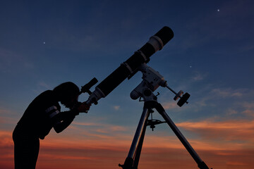 Girl with astronomical telescope stargazing under twilight sky.