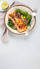 Baked salmon with vegetables on light background.