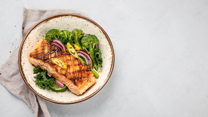 Baked salmon with vegetables on light background.