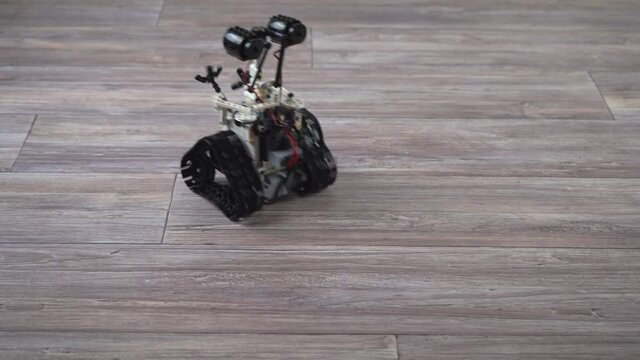 The robot from the children's designer on the control panel. DIY educational toy. A radio-controlled robot rides on the floor. Robotics in action.