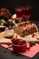 Cranberry sauce with Traditional French terrine on dark wooden background with Christmas decorations