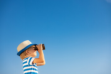 Child looking through binoculars in summer - obrazy, fototapety, plakaty