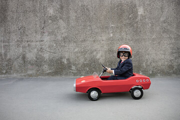 Funny businessman driving retro pedal car outdoor - obrazy, fototapety, plakaty