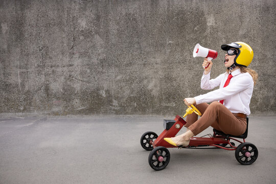 Funny businesswoman driving retro pedal car outdoor