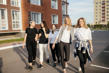 Fototapeta premium Group of young happy girls is walking around the city, having fun and laughing. Concept of relaxation and girly friendship