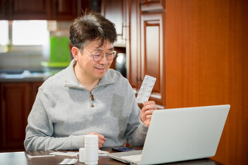 Middle-aged Asian male receiving telemedicine at home.