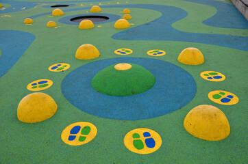 blue rubber surface of a playground with yellow scoops and colored spots in the frost of human...